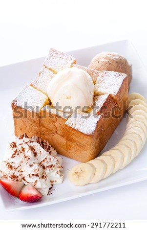 Honey toast with vanilla ice-cream and whipping cream, honey, Strawberry and banana slices on plate