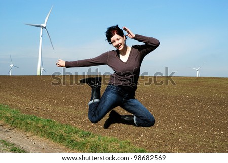 happy woman jumps in front of a wind park