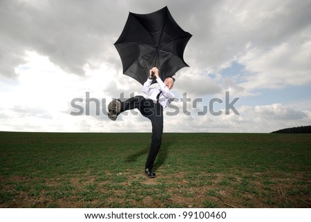 man in business clothing with fights with his umbrella outdoors