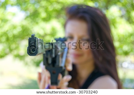 Woman firing with pneumatic gun, focus on gun point