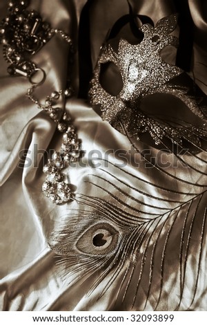 Masquerade mask, beads and feather in sepia