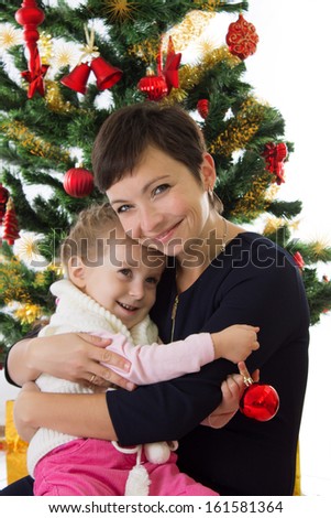 Happy mother hugging daughter under Christmas tree