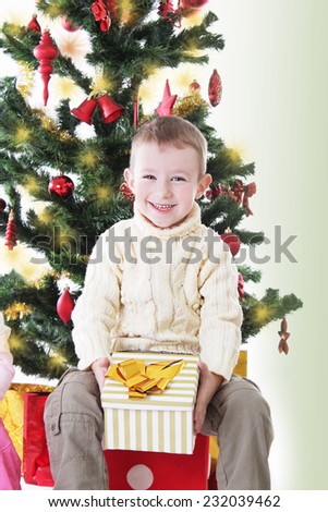 Happy smiling boy with present under Christmas tree
