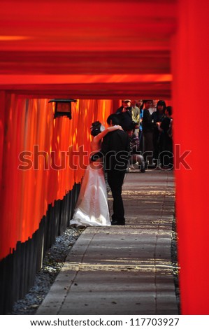 KYOTO, JAPAN - APRIL 9 2012: A Japanese couple takes their wedding photos at Fushimi Inari Shrine on April 9 2012. The shrine is famous for its torii gates walkway that lead to the top of the mountain