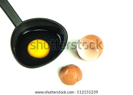 Broken brown egg with raw egg in black spoon
