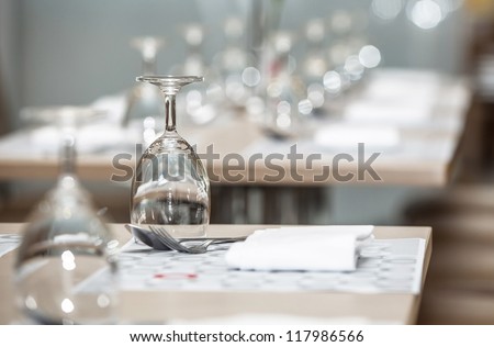 Glasses of water lined up on luxury table setting for dining, selective focus with bokeh background