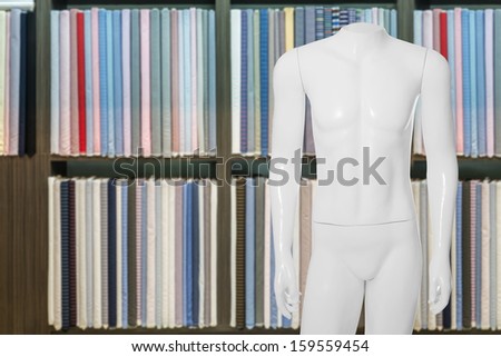 white model dummy headless in tailor shop with fabric swat in the background