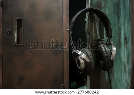 Still life with dramatic lighting image of headphone hang on the opened old high school locker