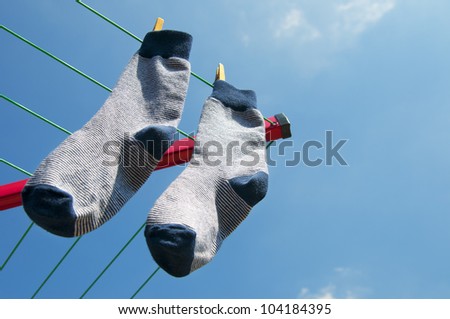 Pair of socks on the clothesline hanging outside to dry in the sun on a warm summer day. Blue striped socks
