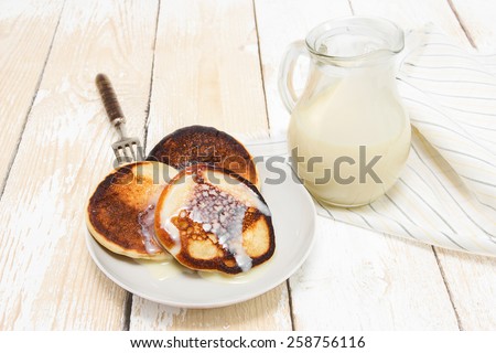 Pancakes with condensed milk on the wooden background