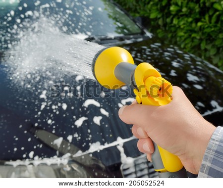 Car care - Woman using a garden spray gun to remove the soap