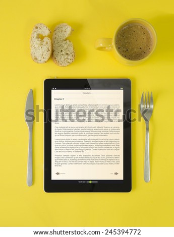 digital book concept: hipster breakfast with book on tablet device, coffee and bread in yellow style