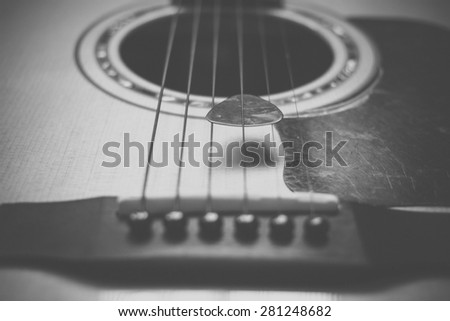 Part of guitar and guitar pick body close up in black and white