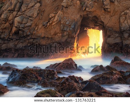 Majestic Light Golden light shining through a natural window in a massive rock formation Big Sur, California