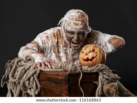 mummy in the dark studio with pumpkin and rope