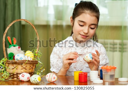 beautiful girl colored Easter eggs sitting at the table