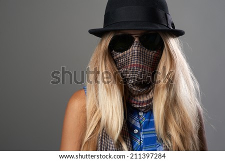 girl hides her face under a scarf and sunglasses