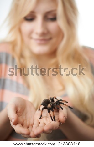 girl holding a large spider on her hands and smiling