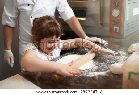 little girl learns to roll out the dough