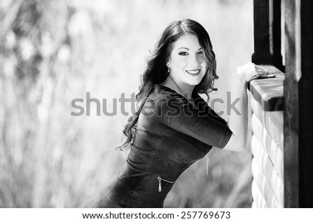 Beautiful girl in a dress with long hair on nature near a wooden house, black and white