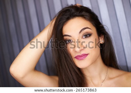 Beautiful brunette girl with charming smile, with the reflection of the stars in the eyes on the background of the striped wall. Star look. Starry glow. Bright eyes.