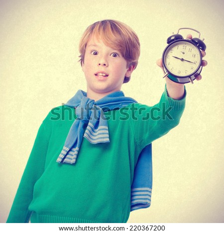 Child holding an alarm clock and concerned about the time