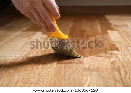 Varnishing lacquering parquet floor by paintbrush - second layer. Home renovation parquet. Varnish paintbrush strokes on a wooden parquet. Application of a highly glossy parquet lacquer Foto stock © 