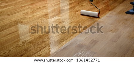 Lacquering wood floors. Worker uses a roller to coating floors. Varnishing lacquering parquet floor by paint roller - second layer. Home renovation parquet Foto stock © 