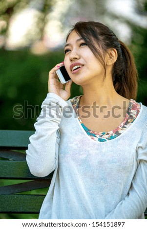 Asian woman talking on iphone cellphone outdoor
