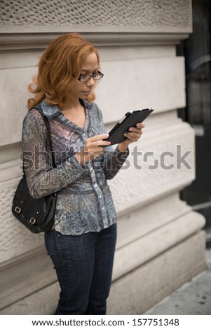 Latin Hispanic Asian woman using tablet pc computer in a city outdoor