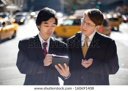 Asian and caucasian businessman in New York City using tablet pc