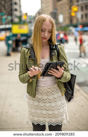 Young blond caucasian woman in New York City using tablet pc on street
