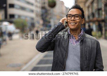 Young Black African Asian mixed man in city talking on cell phone