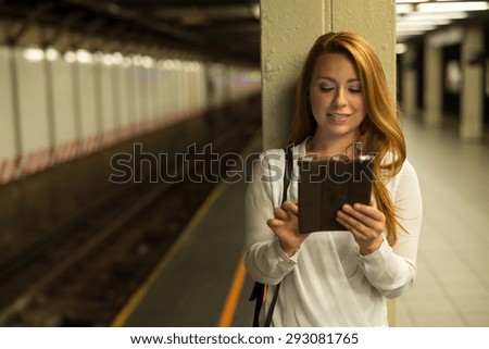 Young Caucasian woman using tablet pc computer at subway platform in New York City