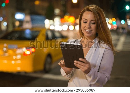 Young Caucasian woman using tablet pc computer at night in city