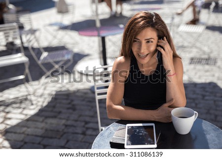 Young Latina Hispanic Caucasian woman at outdoor cafe multitusking