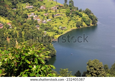 View of some homesteads among orchards on the shore of the 4.43 km2-784 ms.high Phewa tal-lake seen from the way down Ananda Hill and opposite Pokhara city. Kaski district-Gandaki zone-Nepal.