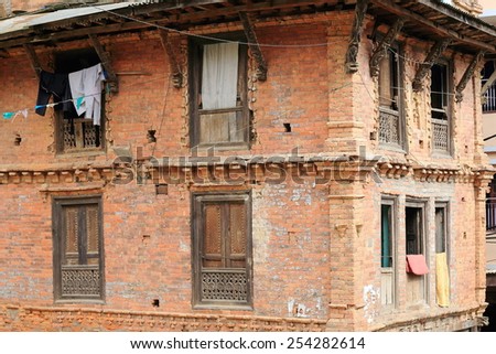 Traditional newar style red brick old house with carved wooden windowsills and roof struts-clothes hanging in the old city area. Dhulikhel-Kavrepalanchok distr.-Bagmati zone-Nepal.