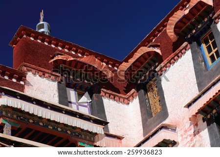 Colorist wooden windows-fabric edgings-dhvaja or victory banner on the roof-white washed walls of the Drepung-Rice heap monastery of Gelugpa-Yellow Hat order. Foot of mount Ghephel-Lhasa pref.-Tibet.