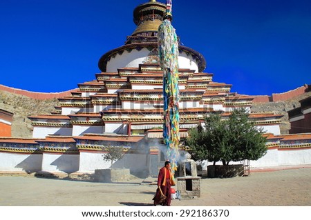 GYANTSE, TIBET, CHINA - OCTOBER 23: Buddhist lama cares the fire lit in the yard of the Kumbum-Tashigomang pagoda of 9 tiers-76 shrines on October 23, 2012. Gyantse city and cty.-Shigatse pref.-Tibet.