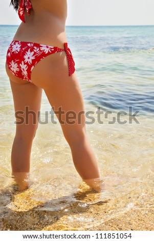girl with a beautiful figure on the beach sunning on the beach, red swimsuit on a girl with elegant figure