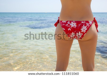 girl in a red bikini at sea, girl tanning on the beach in a red bathing suit