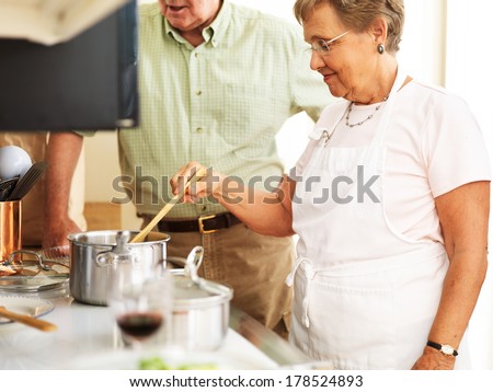 elderly married couple cooking food in the kitchen