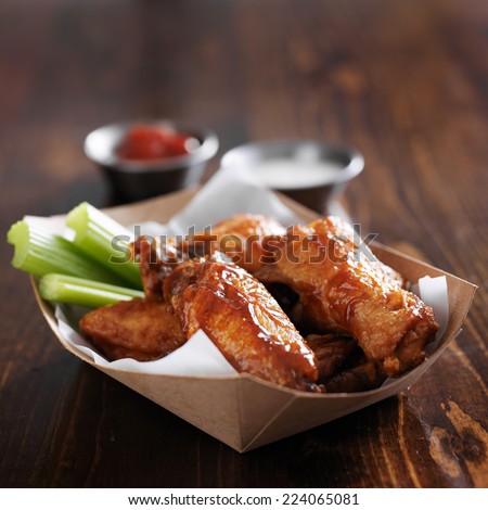barbecue buffalo chicken wings with celery sticks and ranch sauce in basket