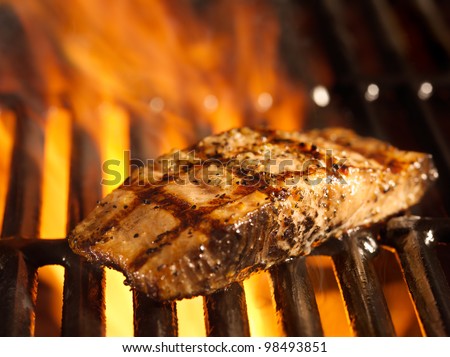 salmon fillet on the grill with flames in horizontal orientation