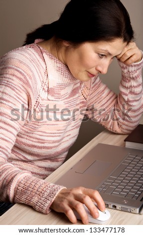 Senior woman with a laptop,  relaxing on the couch.