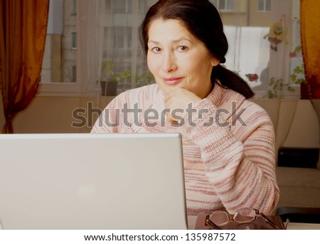 Senior woman with laptop, relaxing on the couch.