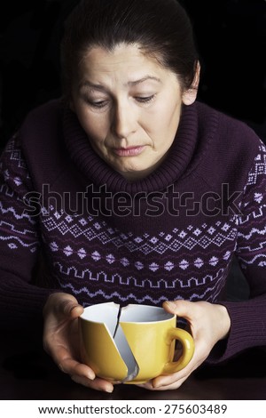 Woman with the broken cup in hand on a black background.