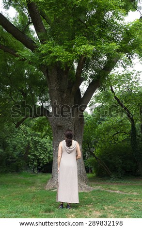 A mature woman near a tree in the park. Health, nature concept.