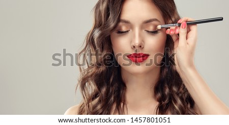  Makeup artist applies  eye shadow  . Beautiful woman face. Hand of visagiste, painting  cosmetics of young beauty  model girl . Make up in process Stock foto © 